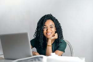 Employee smiling at the camera behind a laptop at her desk