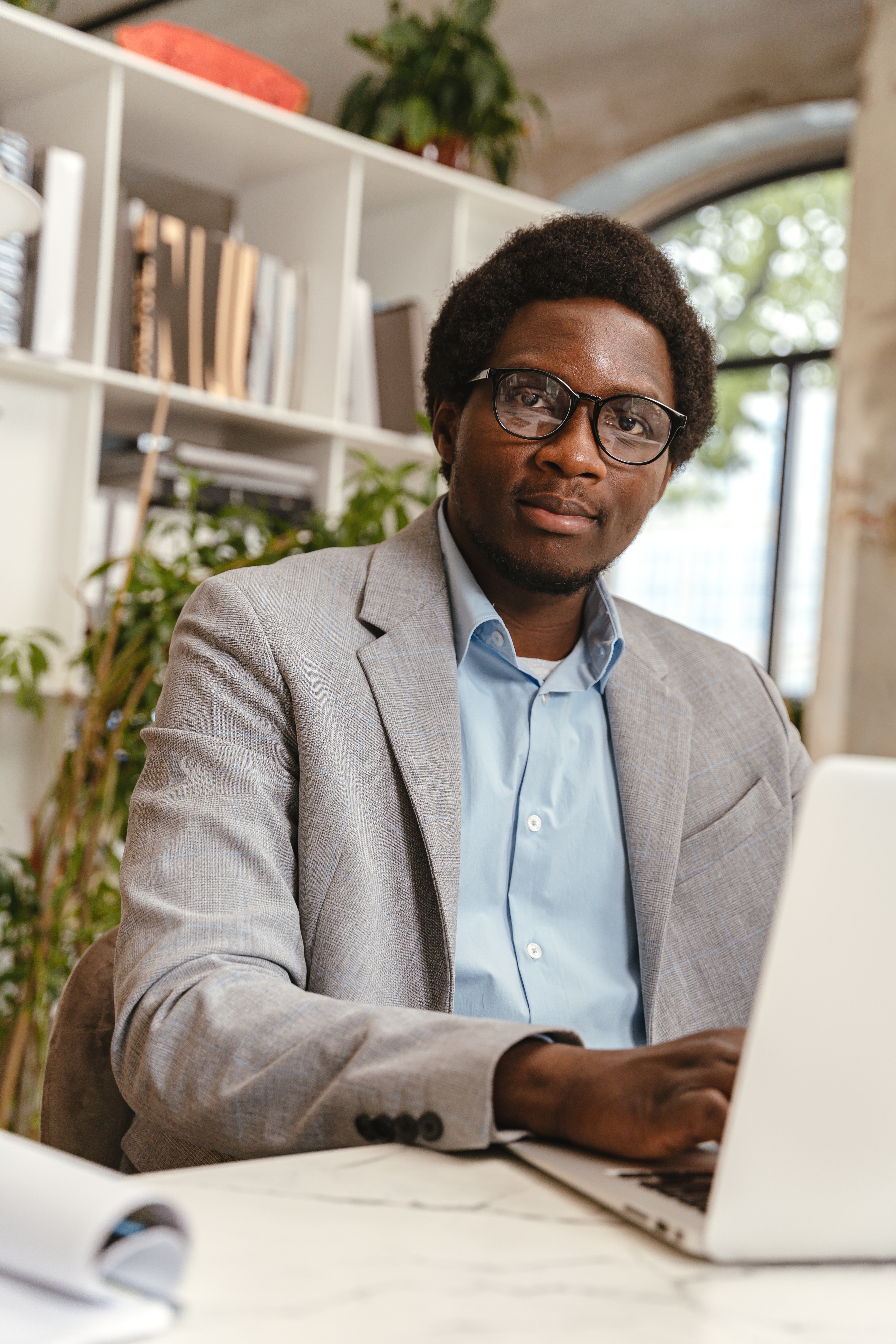 Office worker at their desk using a laptop and looking directly at the camera