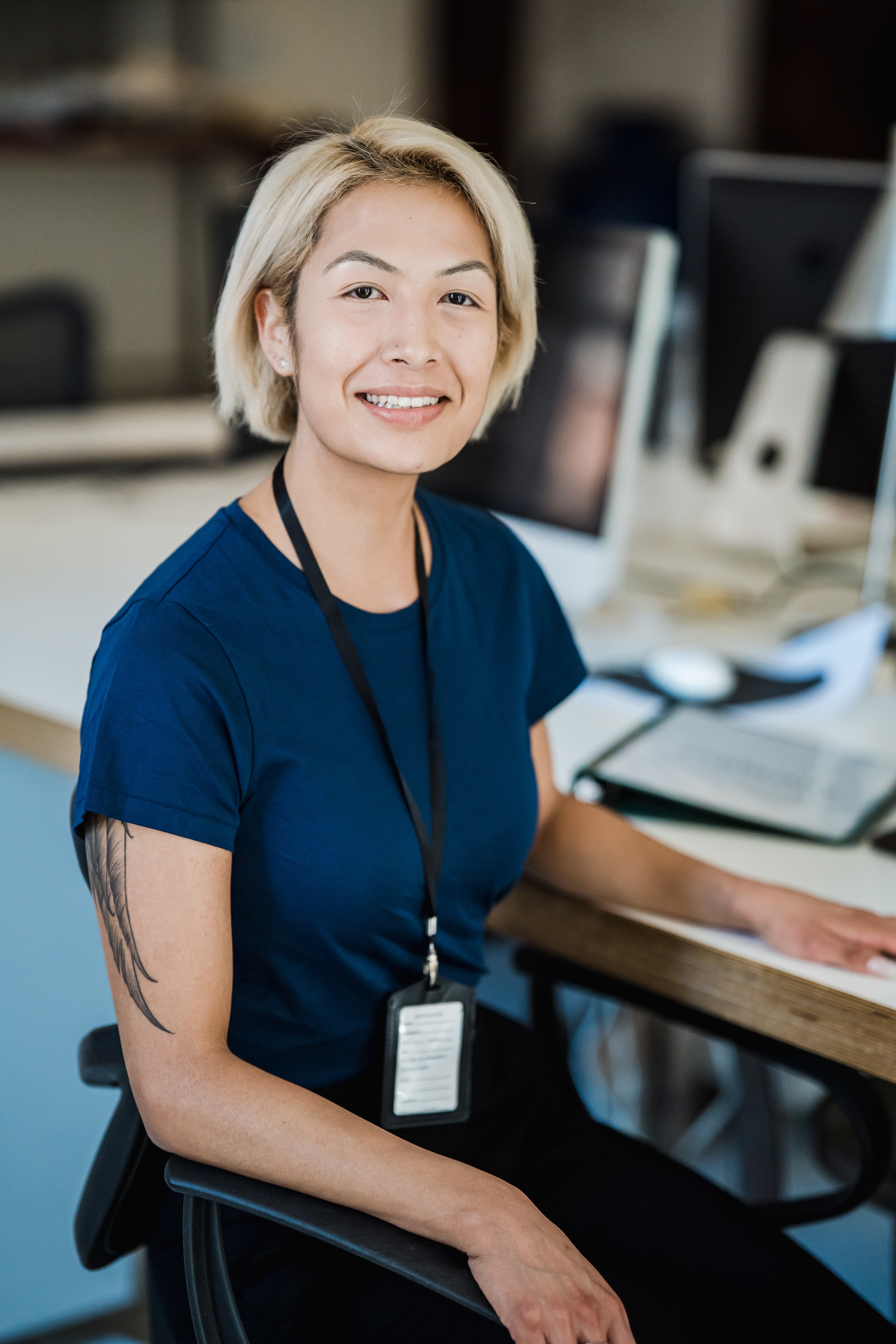 Smiling employee sitting at a desk with folders and screens in the background