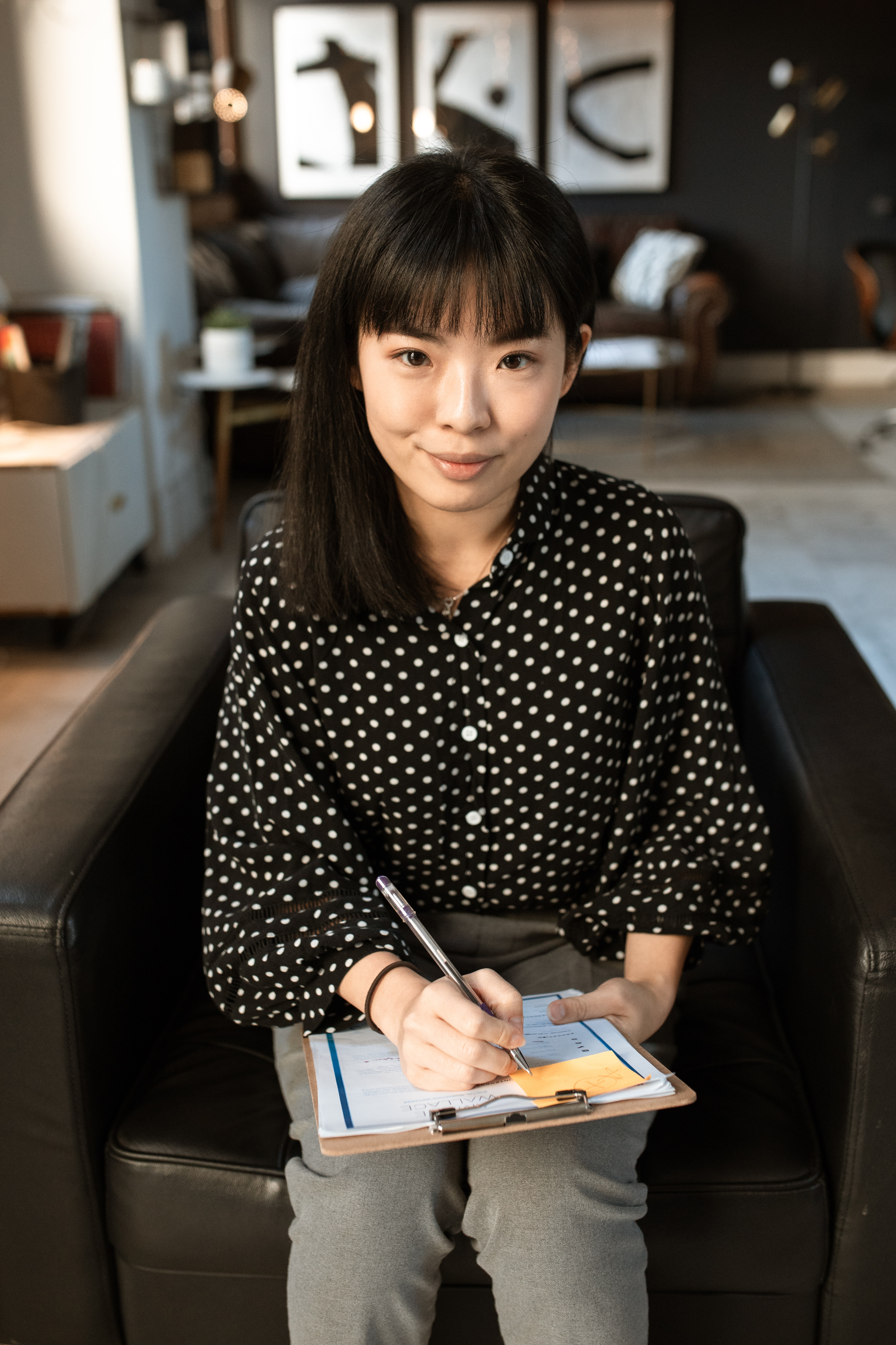 Employee with a clipboard sitting in a leather chair and looking at the camera